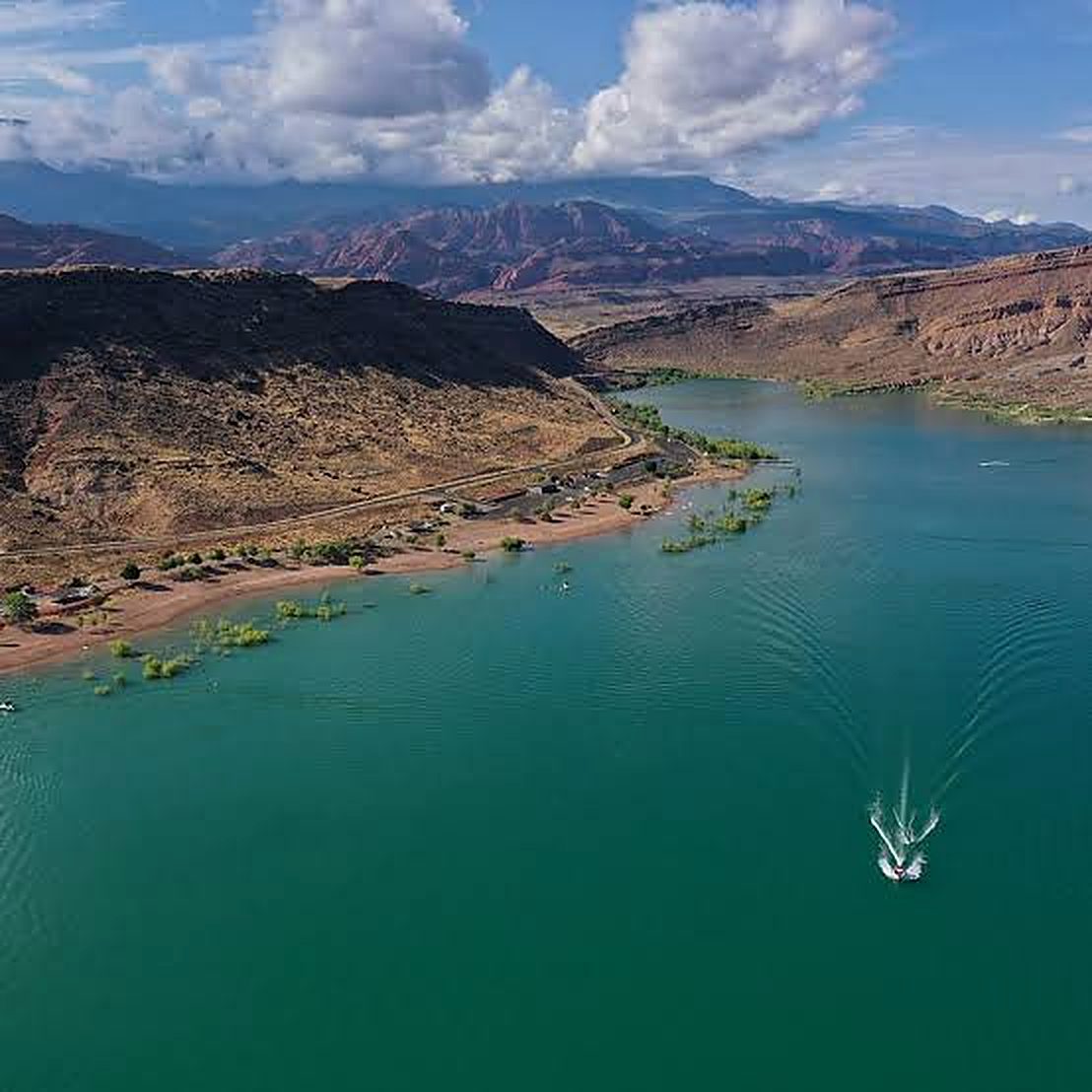 Aerial view of Quail Creek Reservoir with turquoise water and a boat leaving a long wake