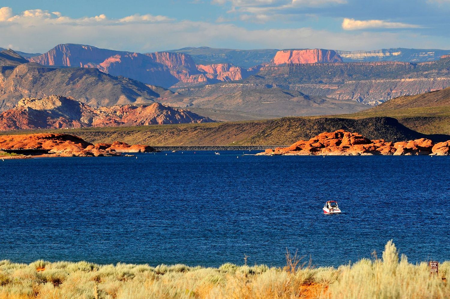 Sand Hollow Reservoir near St. George with deep blue water, red sandstone shoreline and distant red rock cliffs